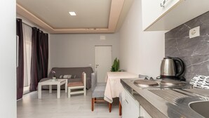 Una cocina compacta con encimera de mármol, cafetera y zona de comedor con mesa y sillas.
