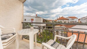 Un balcón con mesa y sillas, con vistas a una zona residencial de tejados rojos.