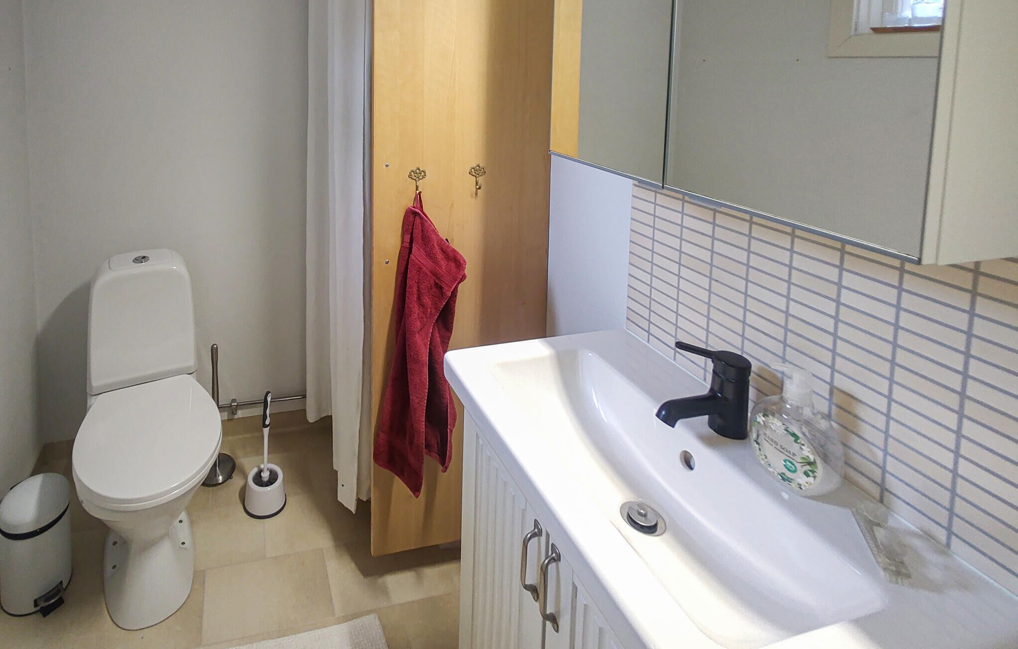 A bathroom with a white toilet, a white sink with a black faucet, and a mirror above the sink.