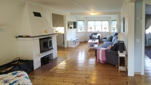 Ein gemütliches Wohnzimmer mit Kamin, einer Couch, einem Fernseher und einem Essbereich.