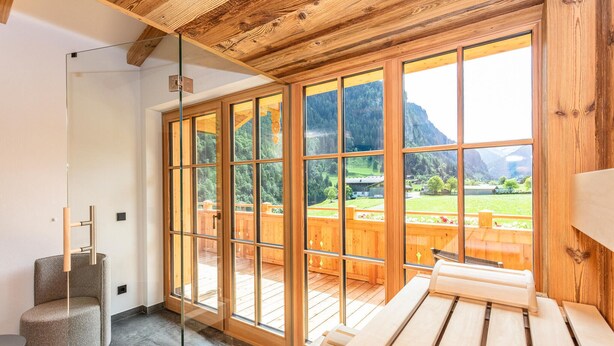 Quarto com janelas amplas, deck de madeira, sauna e mesa de massagem.