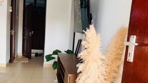 A modern living room with a wooden cabinet, a TV mounted on the wall, and a decorative plant. - Cozy bed & breakfast in charming Mombasa County with WiFi (Mombasa County)