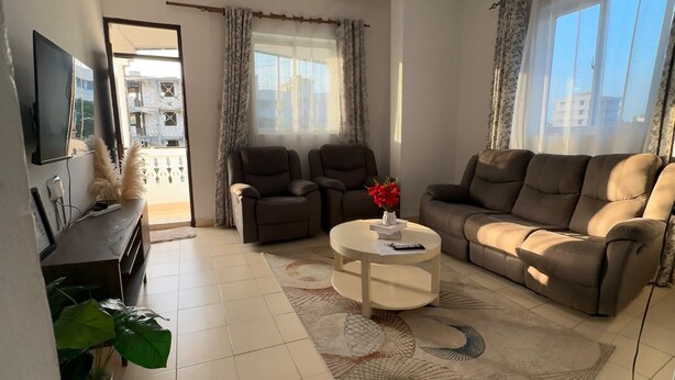 A living room with a sofa, chairs, a coffee table, and a TV. - Cozy bed & breakfast in charming Mombasa County with WiFi (Mombasa County)