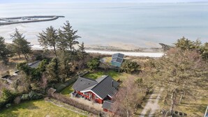 A coastal property with a main house featuring a sloped roof, a secondary building, and a beach view.