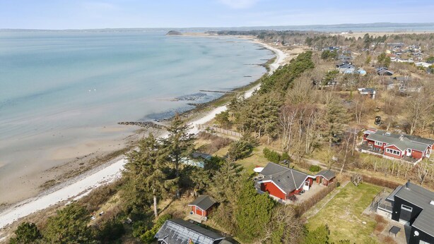 An aerial view of a coastal residential area with houses, a beach, and a clear sky.