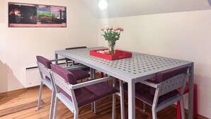 A dining area with a table and chairs, a vase with flowers, and a painting on the wall. - Cozy apartment in Søgne with house sea view (Søgne)