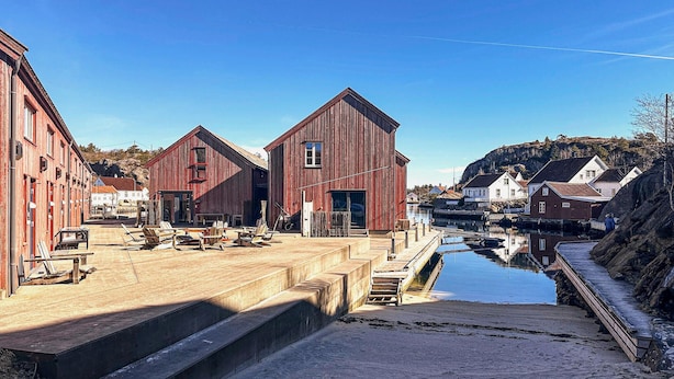A waterfront property with wooden buildings, a dock, and a calm water body. - Cozy apartment in Søgne with house sea view (Søgne)