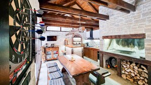 A cozy room with a dartboard, a wooden table, and a fireplace. - Stunning home in Mrkopalj with sauna (Mrkopalj)