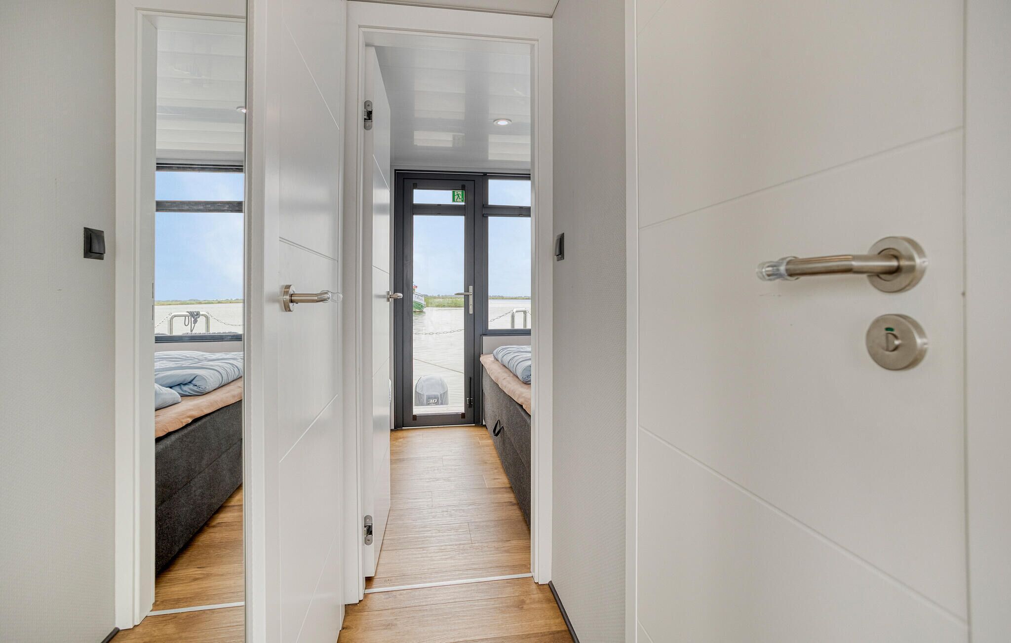 Un couloir menant à une chambre avec un lit et une vue sur la mer.