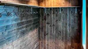 Een hoekkast met houten lambrisering en metalen haken om spullen aan op te hangen.