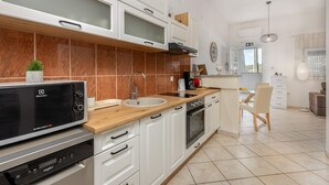 Una cocina moderna con armarios blancos, encimera de madera, horno empotrado y microondas.