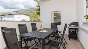 Un patio con mesa y sillas, una parrilla y vistas a la montaña.