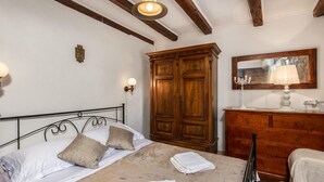 Een slaapkamer met een bed, een houten garderobe en een spiegel.