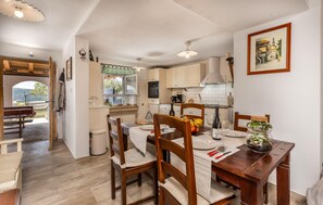 Cozy living and dining area with a dining table for two, kitchenette, and outdoor views.