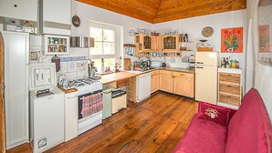 Una cocina compacta con armarios de madera, una estufa y un sofá rojo en la sala.