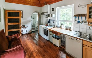 Une cuisine avec un plancher en bois, une cuisinière, un évier et une fenêtre.