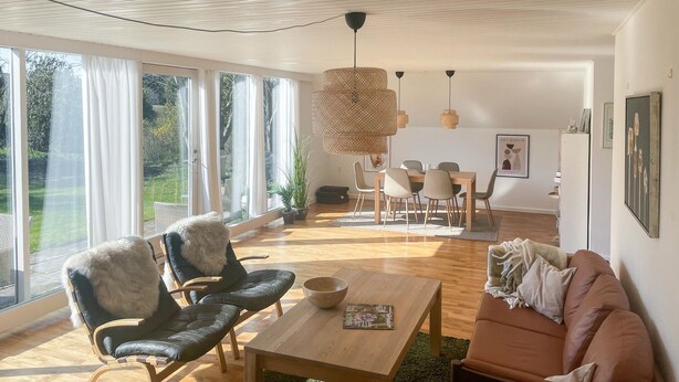 A spacious living room with a large window, a dining area, and a cozy seating area.