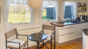 A compact kitchen with a dining area, large windows, and a view of the outdoors.