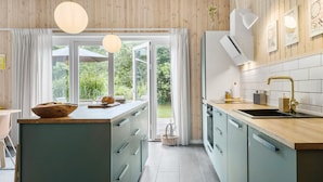Een moderne keuken met een groot eiland, houten kastjes en uitzicht op buiten.