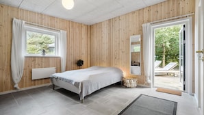 Een slaapkamer met een bed, nachtkastje, spiegel en uitzicht.