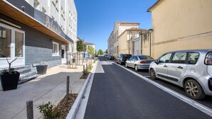 Une rue étroite bordée de voitures garées et d’immeubles.