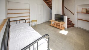 A bedroom with a bed, a TV on a wooden stand, a small stool, and a staircase. - Lovely home in Orange with WiFi (Orange)