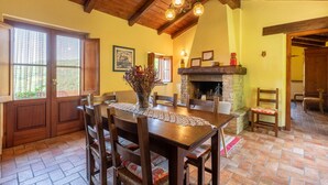 Un coin repas avec une table et des chaises en bois, un vase rempli de fleurs, une cheminée et un plafond en bois.
