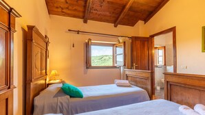Une chambre avec deux lits, une fenêtre donnant sur un beau paysage, des meubles en bois et un miroir.