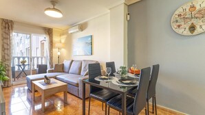 Un salon moderne comprenant un canapé, une table à manger avec des chaises, une table basse et une grande horloge murale.