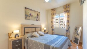 Une chambre à coucher avec un lit, des tables de chevet, un tableau, une fenêtre avec des rideaux et un miroir.