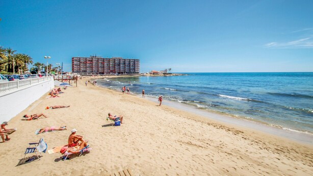 Une plage avec un grand hôtel en arrière-plan.