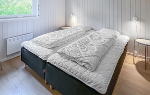 Un dormitorio con cama, mesitas de noche, una ventana y un radiador.