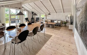 A spacious living area with a large wooden dining table, multiple chairs, a sofa, and a fireplace. - Awesome home in Blåvand with sauna (Blåvand)