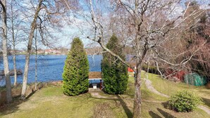 Une propriété au bord du lac, comprenant une petite cabane, un abri de jardin et une pelouse bien entretenue.