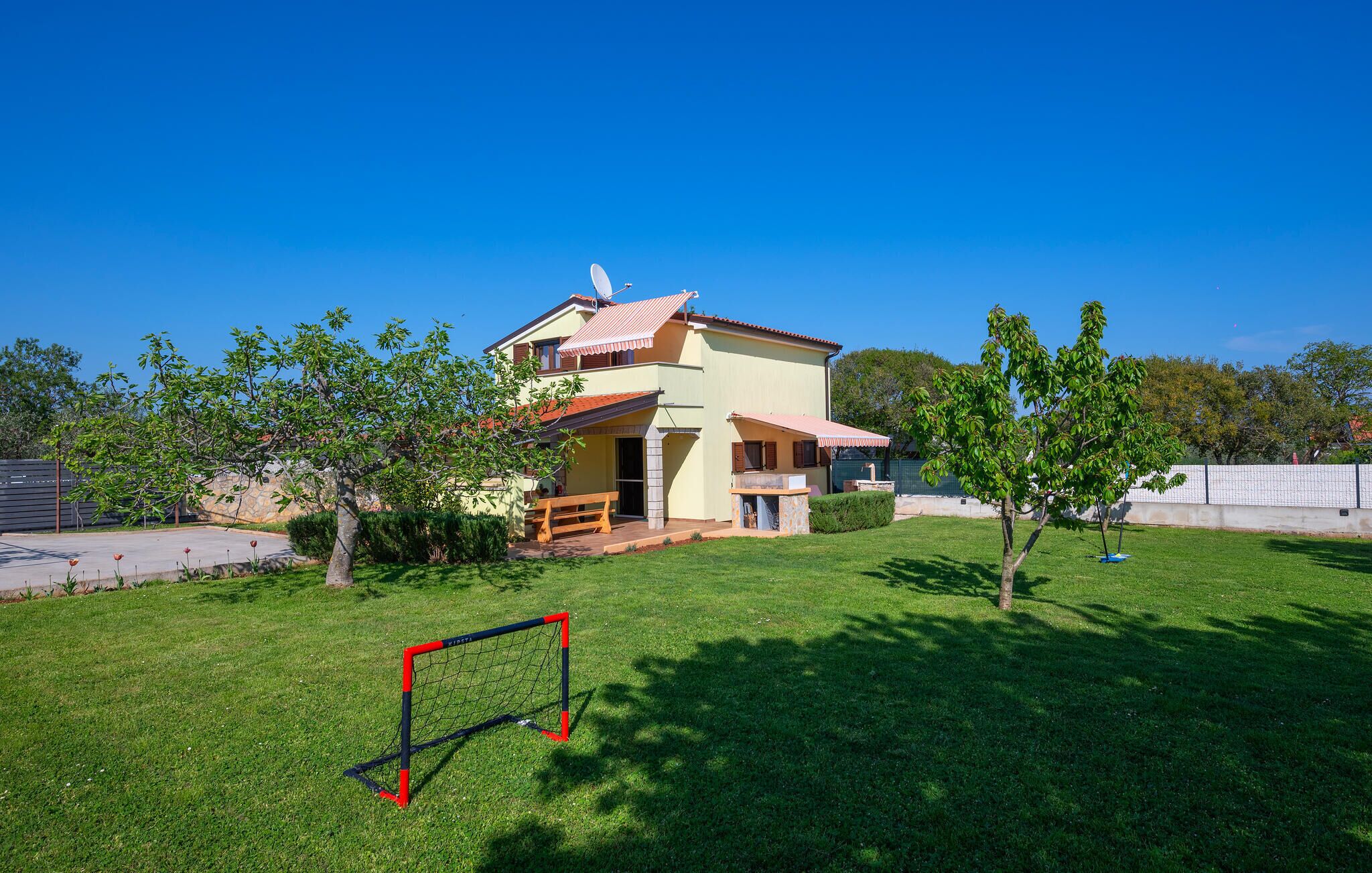 Una casa a due piani con un patio e un piccolo giardino.