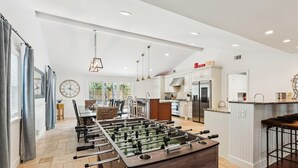 Una cocina amplia con mesa de fútbol, electrodomésticos modernos y barra.