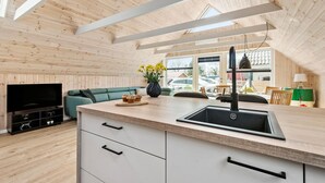 Une cuisine moderne avec un plafond en bois, un évier encastré et une grande fenêtre donnant sur un parking.