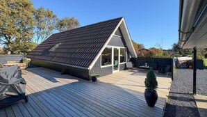 A modern house with a sloped roof, a covered patio, and a fenced backyard.