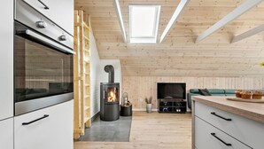 A modern kitchen with a built-in stove, wooden cabinets, and a skylight.