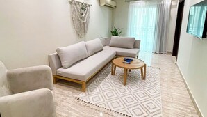 Un salon moderne avec un canapé d’angle beige, une petite table basse ronde et un tapis à motifs.