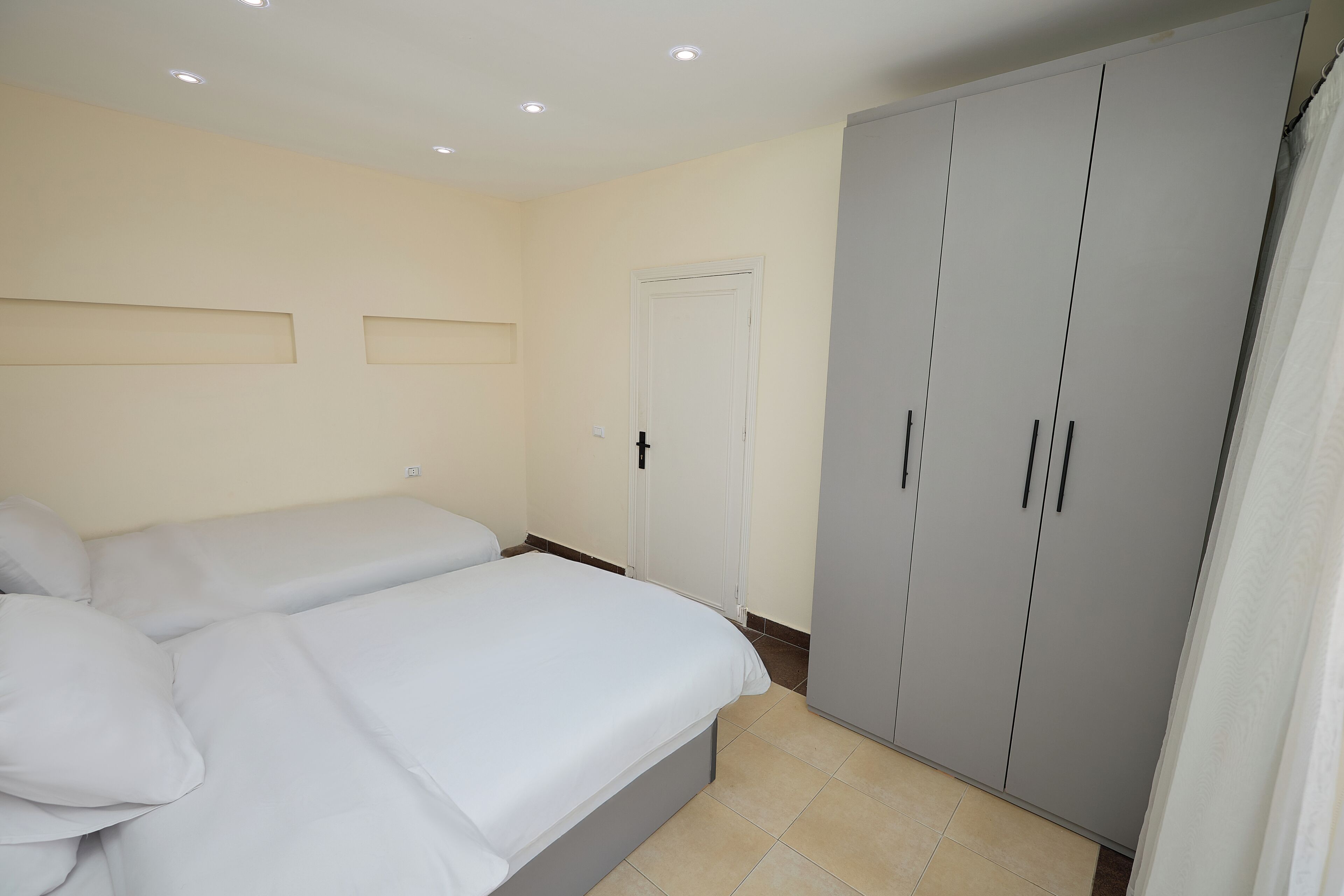 Ein Schlafzimmer mit zwei Betten, einem Kleiderschrank und Einbauleuchten.