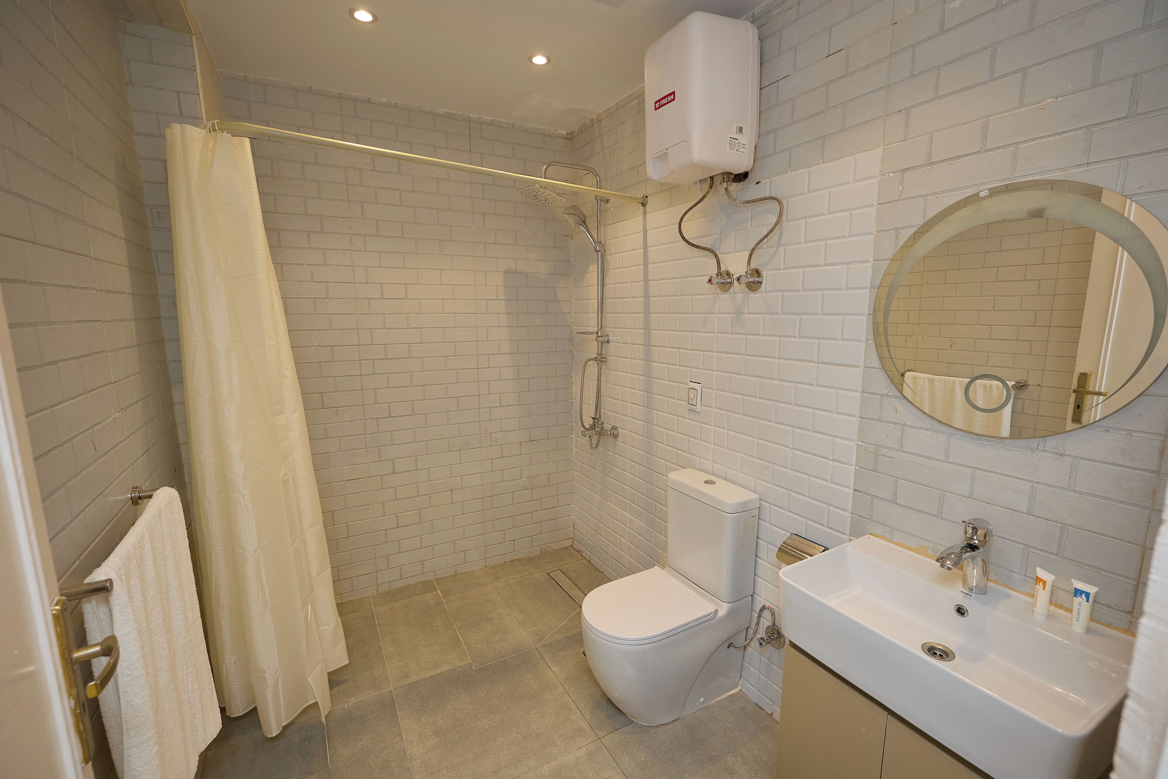Une salle de bain équipée d’une douche, de toilettes, d’un lavabo et d’un miroir.