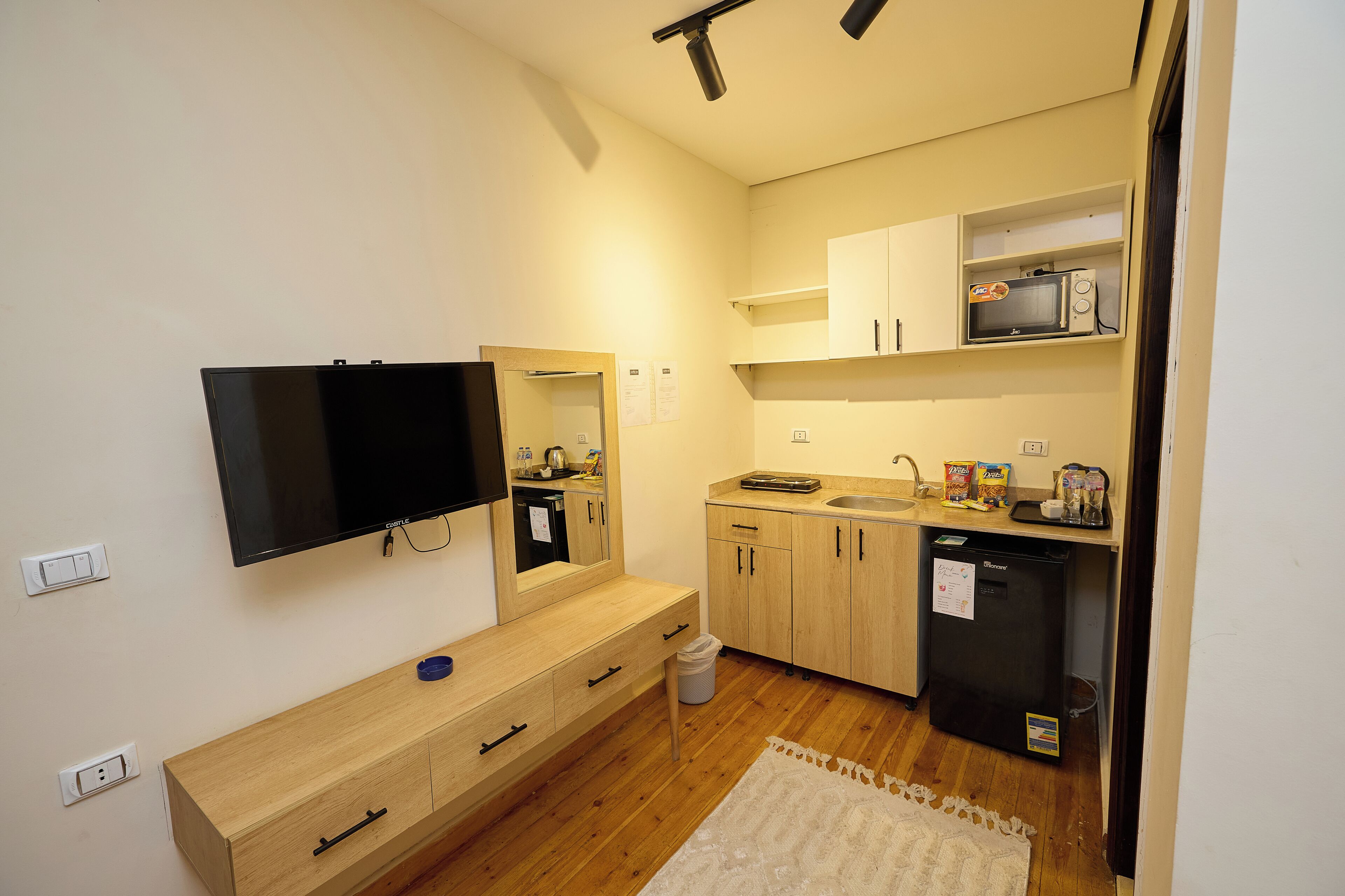 A compact kitchen with a microwave, sink, and a small refrigerator.