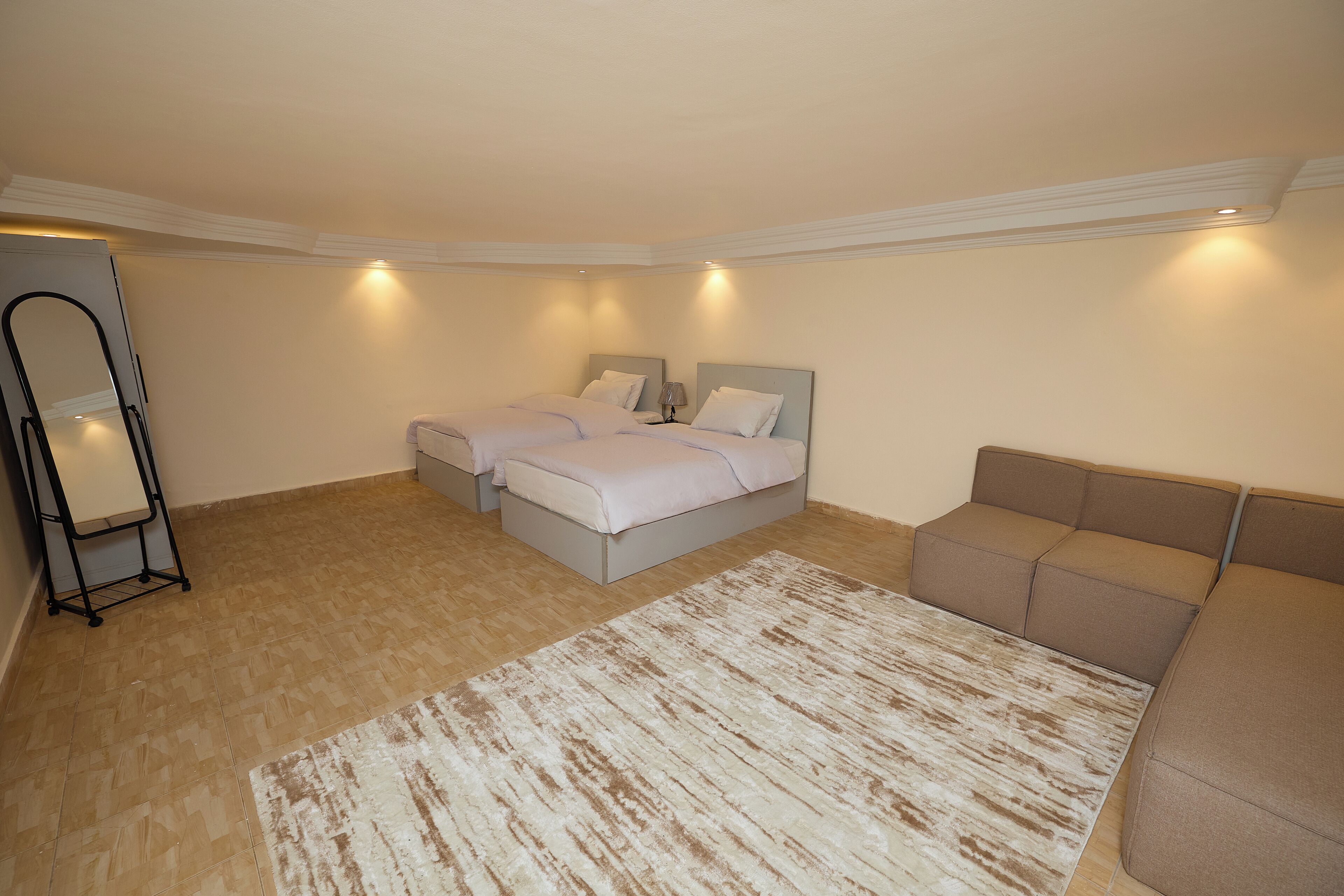 Un dormitorio con dos camas, un sofá, un espejo y una alfombra.