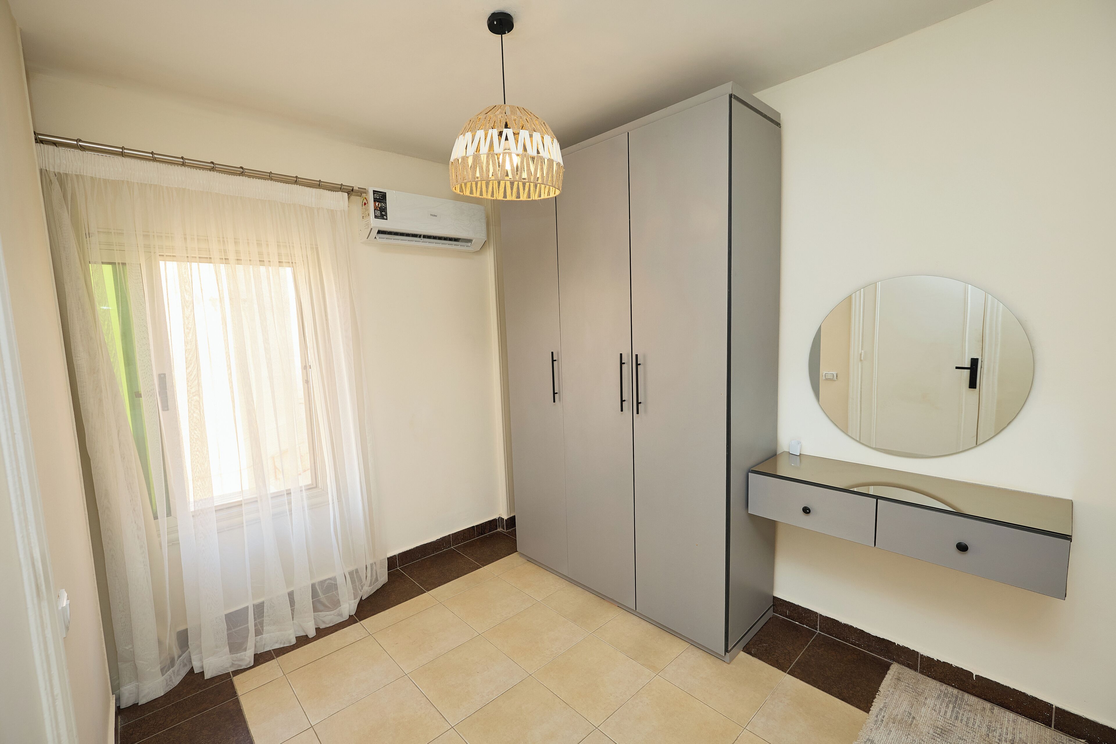 A room with a large wardrobe, a mirror, and a ceiling light fixture.