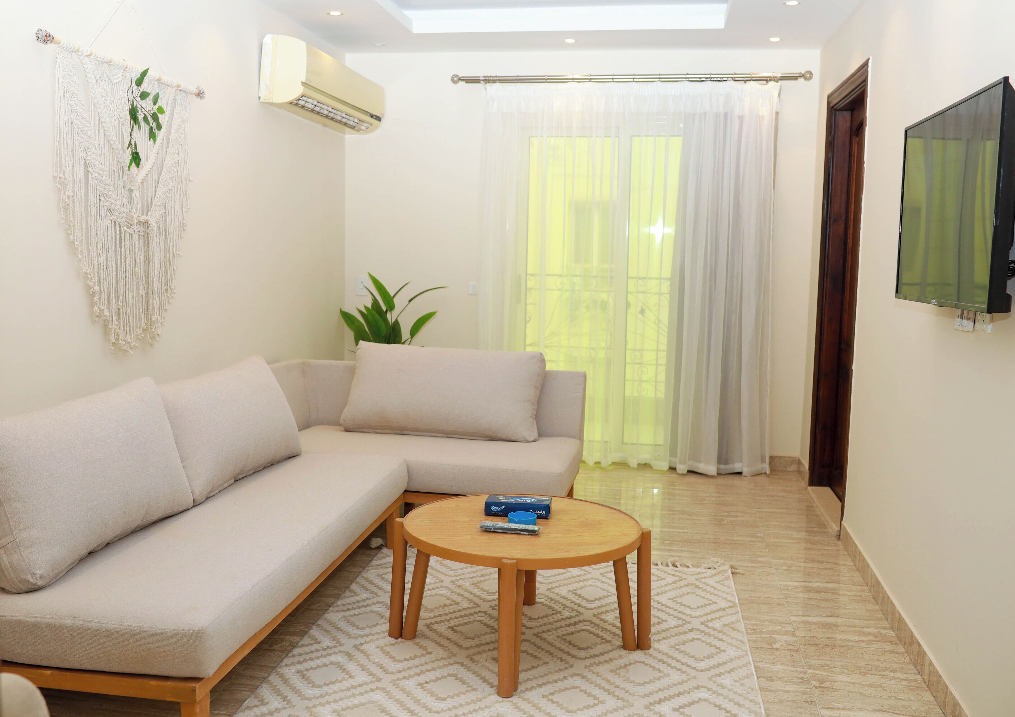 A modern living room with a beige sectional sofa, a small wooden coffee table, and a potted plant.