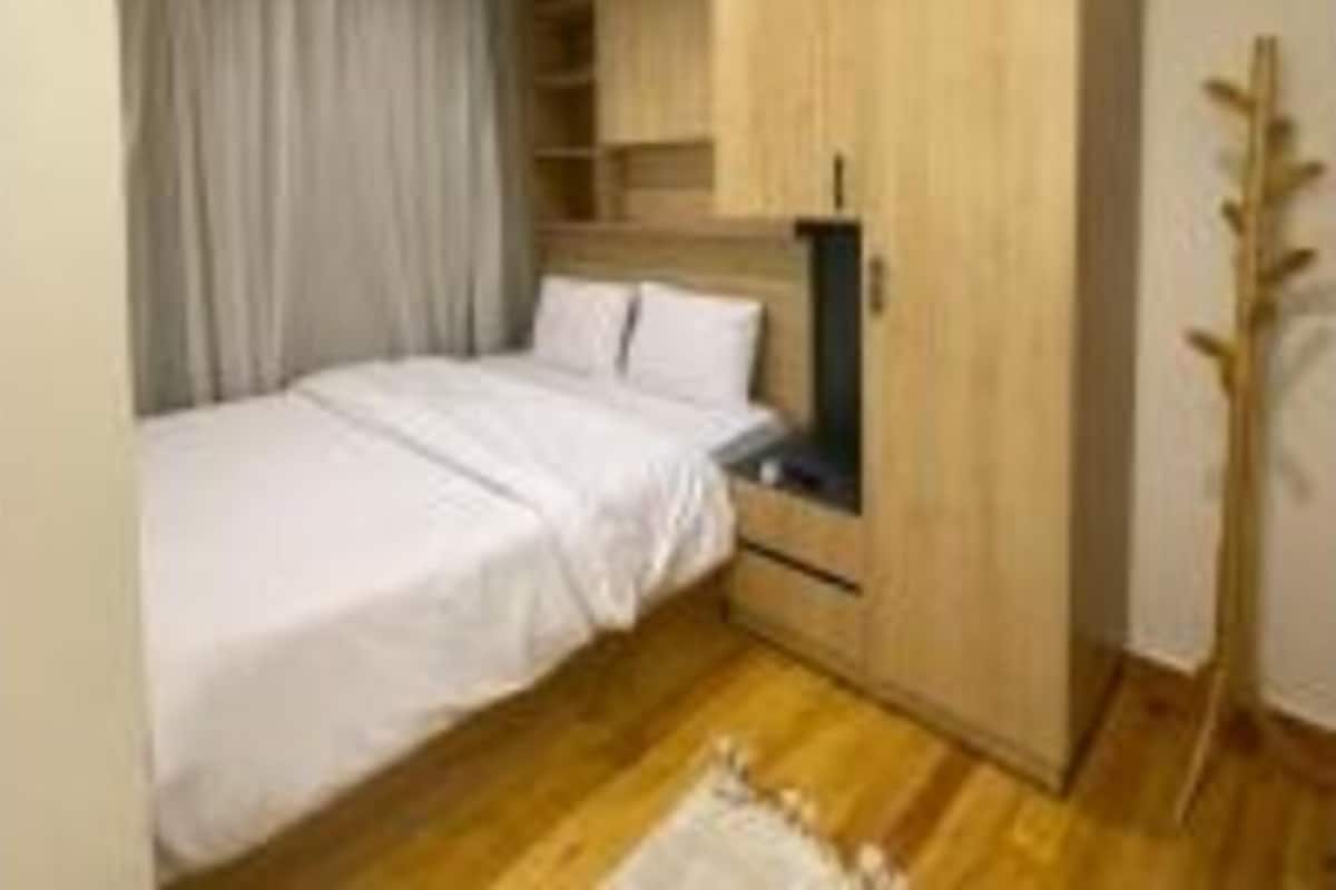 Ένα υπνοδωμάτιο με ένα κρεβάτι, μια ξύλινη ντουλάπα, ένα κομοδίνο και ένα παράθυρο με κουρτίνες.
