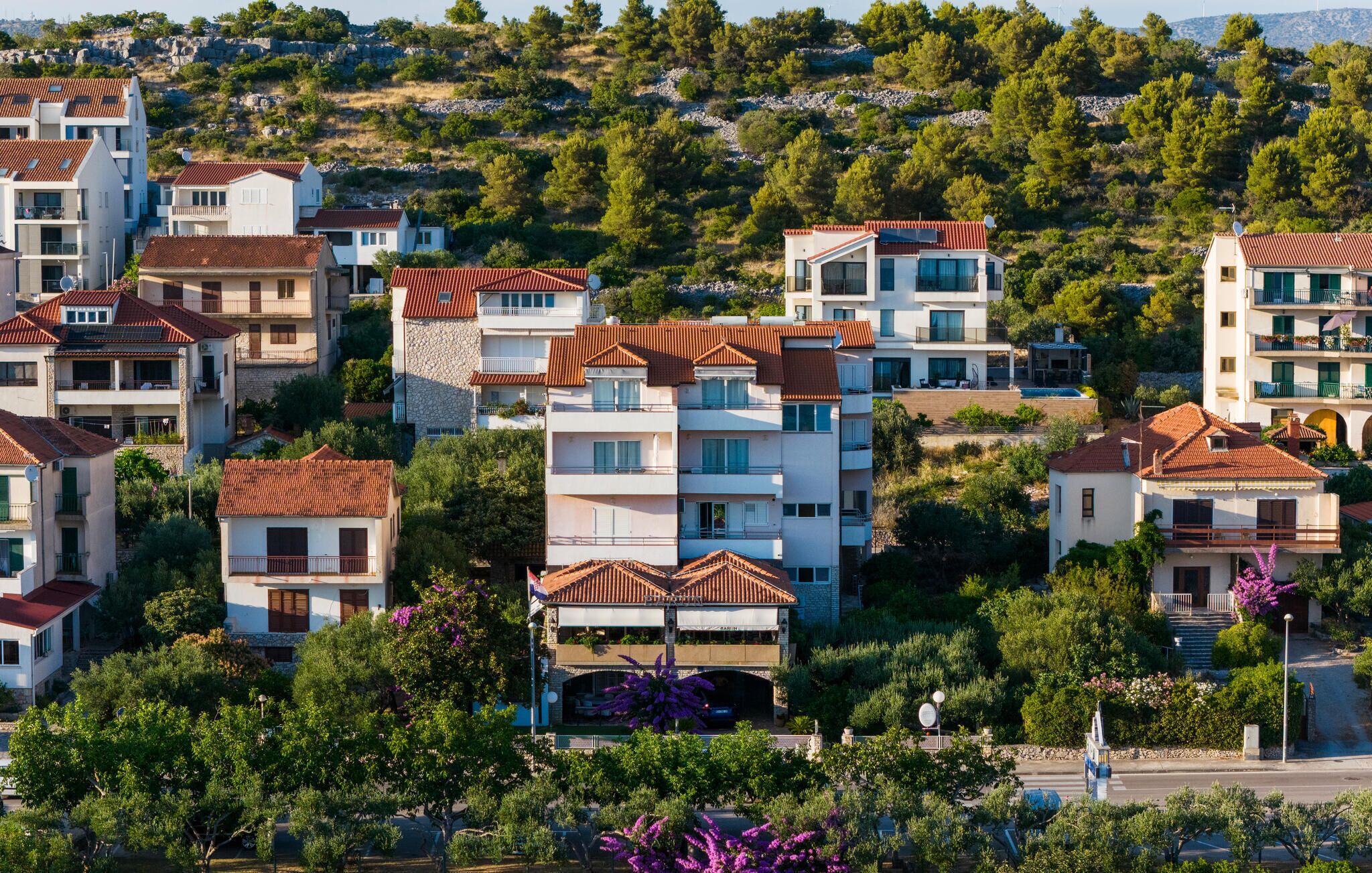 A residential area with multi-story buildings, balconies, and lush greenery.