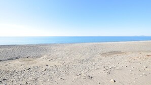 Une plage avec un ciel dégagé et une mer calme.