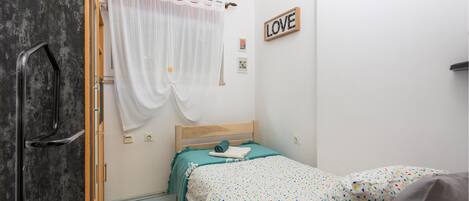A bedroom with a bed, a clock, a 'LOVE' sign, and a curtain.